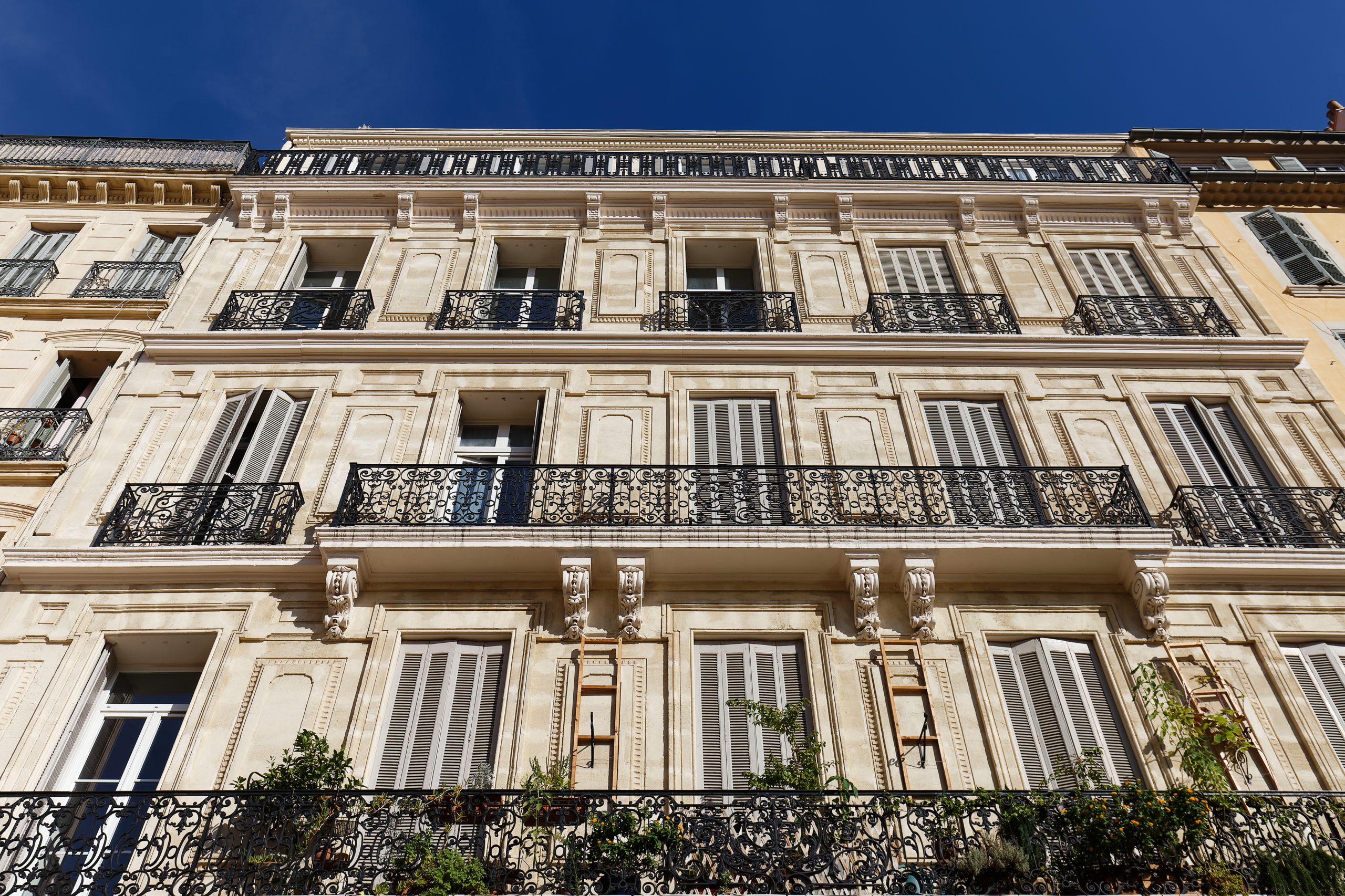 Looking up at the architectural details of an old apartment building in Toulon, France. Beautiful arches, moldings and juliet balconies.