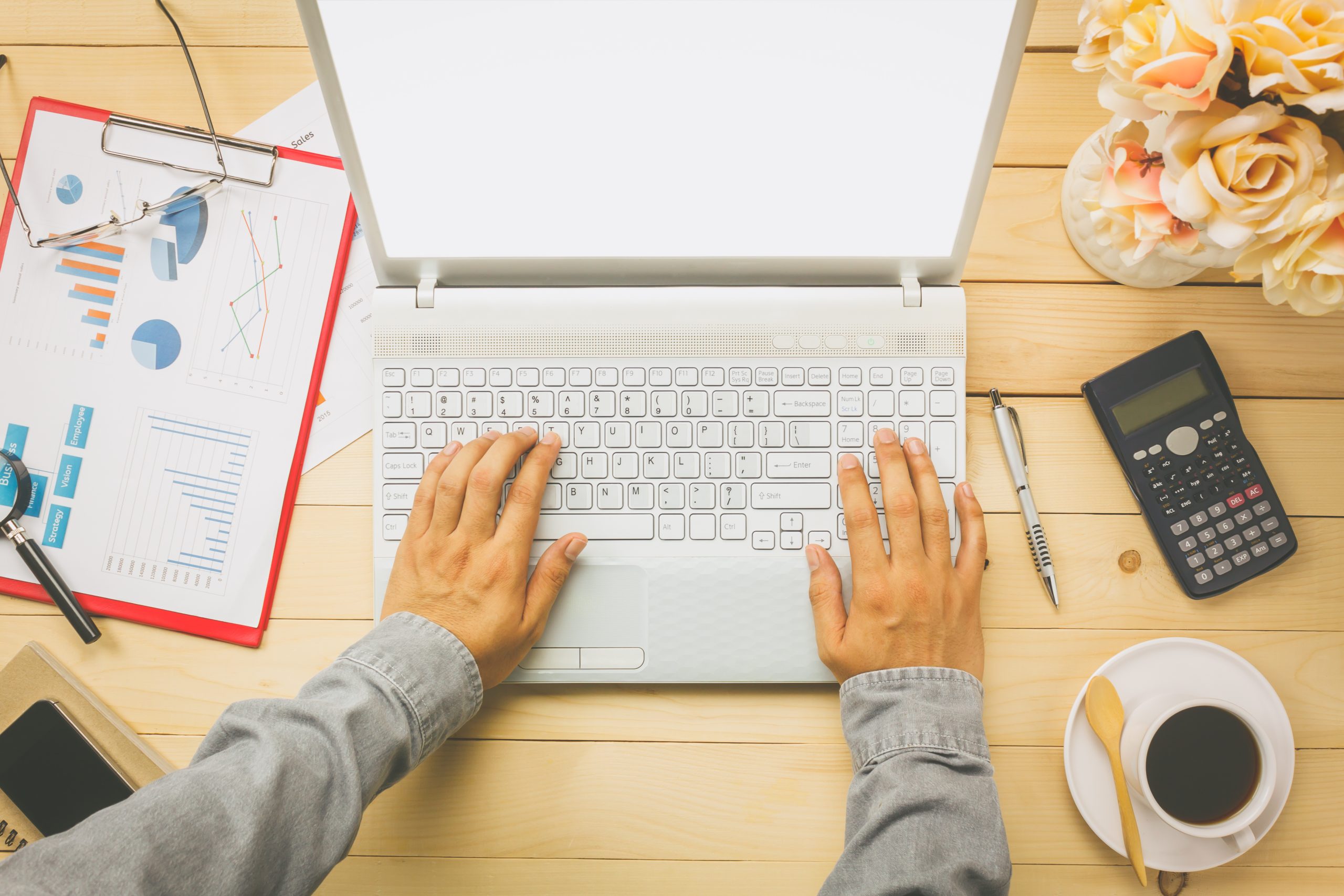 Top view business person discussing charts and graphs with laptop also notebook,black coffee,flower,stationary,pen,calculator on office desk background.